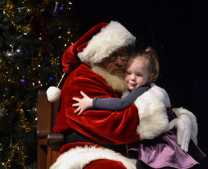 Elodie Page, 4, of Damariscotta, gives Santa a hug after informing him of her Christmas wishes at the Lincoln Theater on Saturday, Nov. 24. (Maia Zewert photo)