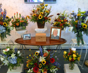 A display of flowers and photos in memory of Samuel E. "Sam" Roberts, publisher emeritus of The Lincoln County News, at the Strong-Hancock Funeral Home in Damariscotta on Thursday, Nov. 15. The bouquet at left holds the Nov. 8 edition of the newspaper, the bouquet at right a pair of his trademark suspenders. (J.W. Oliver photo)