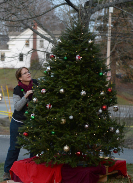 Mary Kate Reny puts the finishing touches on the tree by the Second Congregational Church in Newcastle during the 2017 Villages of Light event. (Paula Roberts photo, LCN file)