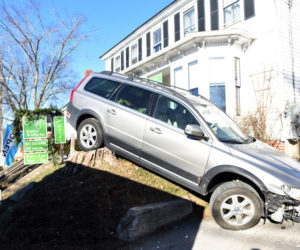 A station wagon at rest on a stump in the front yard of Crissy's Breakfast & Coffee Bar in Damariscotta on Thursday, Dec. 13. The car struck the building while backing up. (Jessica Picard photo)