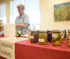Jars of asparagus, pickles, and other goods are displayed on the Erskine Farms table as Iris Erskine helps a customer at the indoor farmers market at the CLC YMCA in Damariscotta, Friday, Nov. 30. (Jessica Picard photo)