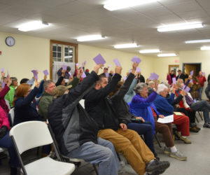 Dresden voters raise their cards to approve the purchase of a 1994 ladder truck during a special town meeting at Pownalborough Hall on Monday, Dec. 10. (Jessica Clifford photo)