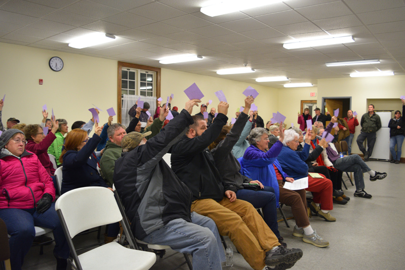 Dresden voters raise their cards to approve the purchase of a 1994 ladder truck during a special town meeting at Pownalborough Hall on Monday, Dec. 10. (Jessica Clifford photo)