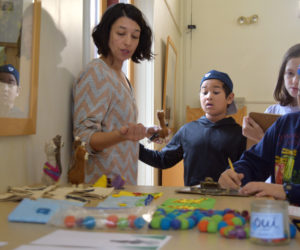 From left: Coreysha Stone, visual arts specialist at the Elementary School at Chewonki, and students Julien King, Ella Seymour, and Lilly Mae Awamleh inventory the goods they will sell at the craft fair. (Jessica Clifford photo)