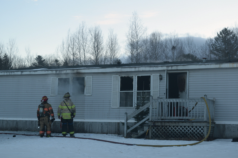 Firefighters look on as smoke drifts from the window of a mobile home fire at 139 Sheepscot Road in Wiscasset the morning of Wednesday, Jan. 16. (Jessica Clifford photo)