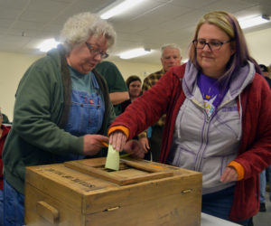 Melanie Gaczi (left) writes her vote on a slip of paper while Karen Silverman places her slip in the ballot box during a special town meeting at Pownalborough Hall in Dresden on Monday, March 11. Voters approved a change from electing to hiring town office staff, 41-14. (Jessica Clifford photo)