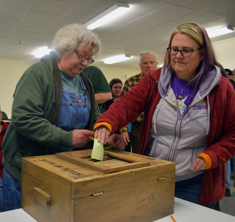 Melanie Gaczi (left) writes her vote on a slip of paper while Karen Silverman places her slip in the ballot box during a special town meeting at Pownalborough Hall in Dresden on Monday, March 11. Voters approved a change from electing to hiring town office staff, 41-14. (Jessica Clifford photo)
