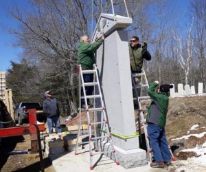 Eighty-two-year-old monument setter Francis Tash, of Barre, Vt., guides the top piece of a monument into place at West Bristol Cemetery in Walpole on Thursday, April 11. Thomas A. Stevens Cemetery Memorials, of Newcastle, and subcontractors worked throughout the day to set up South Bristol's new veterans memorial. (Candy Congdon photo)