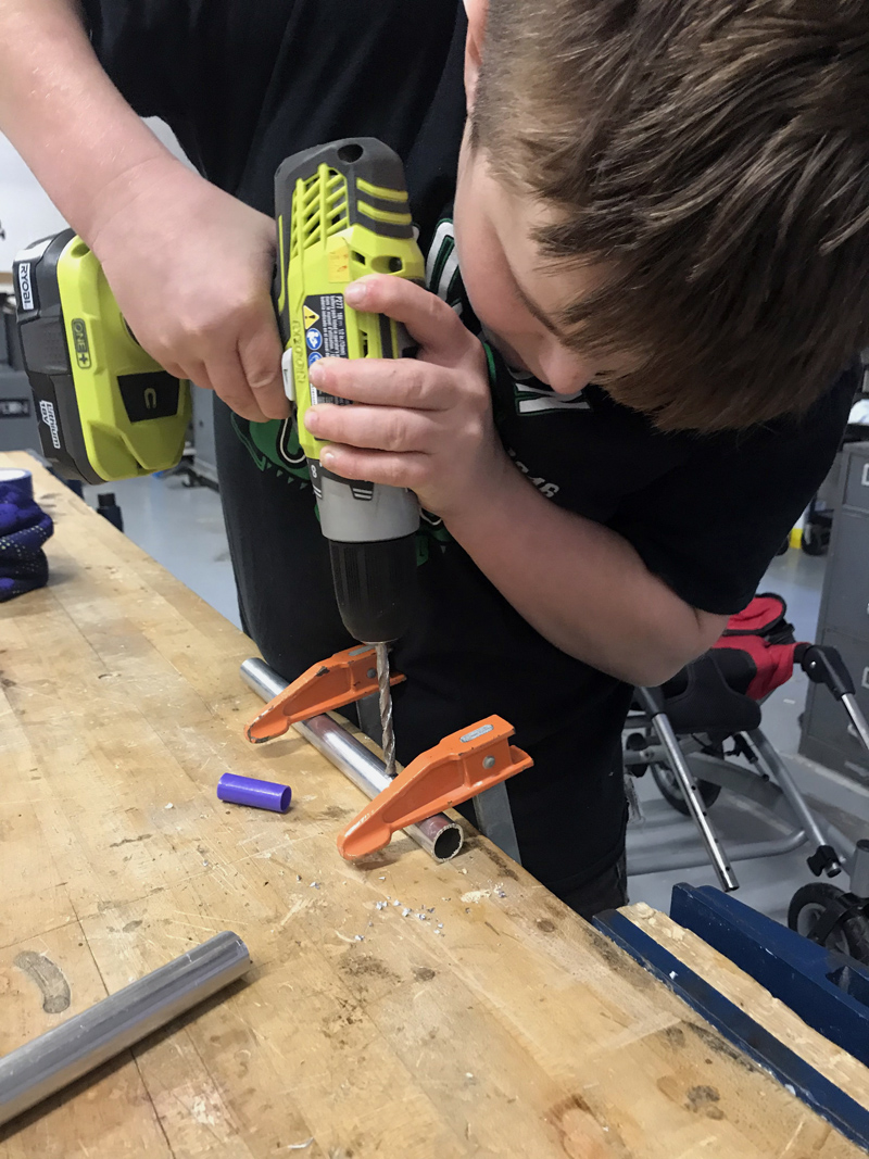 Camden Larrabee, 12, of Wiscasset, drills a hole in a metal tube, which he would go on to use as part of a pedal extension for another 12-year-old's wheelchair. (Photo courtesy Rachel Hamlin)