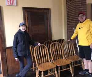 Round Pond Schoolhouse Association President Cynthia Wright accepts an early donation of solid-oak dining room chairs from the Stano family, of Round Pond.