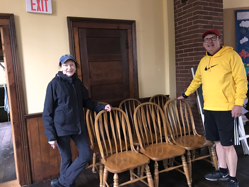 Round Pond Schoolhouse Association President Cynthia Wright accepts an early donation of solid-oak dining room chairs from the Stano family, of Round Pond.