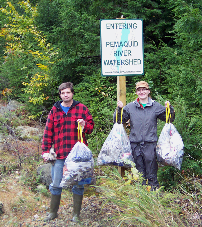 Cleanup volunteers tote bags of roadside trash.