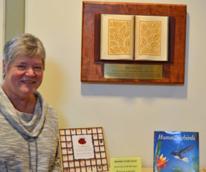 Skidompha Library Executive Director Pam Gormley stands next to her retirement gift, a plaque and sculpture by Damariscotta artist Jaques Vesery. (Evan Houk photo)