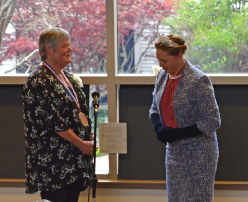 "The queen," portrayed by former Skidompha Library employee Torie Delisle, bows after "knighting" the library's retiring executive director, Pam Gormley, at a high tea in Gormley's honor Sunday, May 19. (Evan Houk photo)