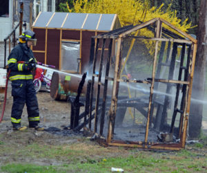 A Newcastle firefighter douses the smoldering remnants of a small chicken coop at 20 Hawthorne Road in Newcastle the morning of Monday, May 20. (Evan Houk photo)