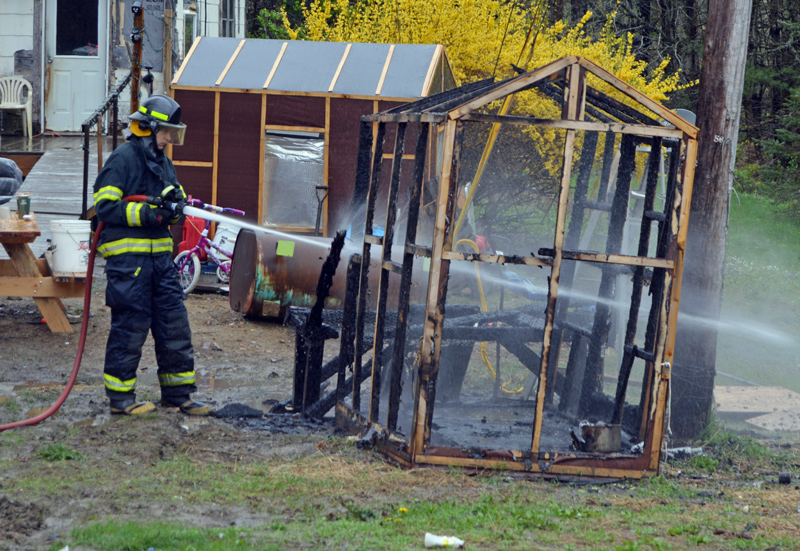 A Newcastle firefighter douses the smoldering remnants of a small chicken coop  at 20 Hawthorne Road in Newcastle the morning of Monday, May 20. (Evan Houk photo)