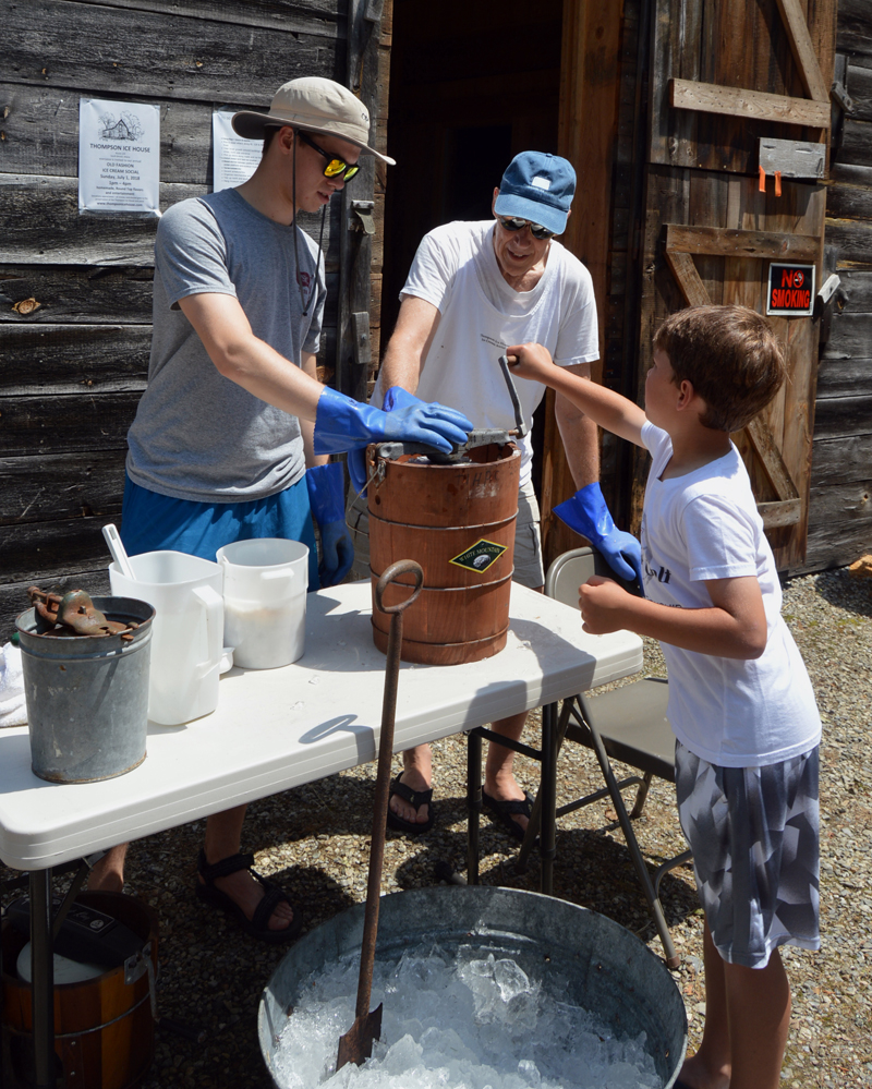 Drew Metzel, 7, cranks ice cream with volunteers Daniel Shaw (left) and Lester McDowell (right) at the 2018 Thompson Ice House ice cream social. (LCN file photo)