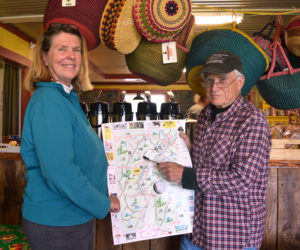 Libbey Seigars, one of the volunteers behind the new Whitefield map and guide, and Bill McKeen, Whitefield selectman and leader of the group, hold up an unfolded copy of the map. (Jessica Clifford photo)