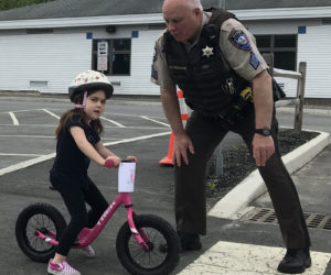 Lincoln County Sheriff's Office Sgt. Mark Bridgham teaches Lucy Leeman how to safely exit a driveway during a bicycle safety rodeo at Bristol Consolidated School on Saturday, June 22.