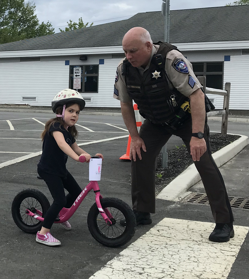 Lincoln County Sheriff's Office Sgt. Mark Bridgham teaches Lucy Leeman how to safely exit a driveway during a bicycle safety rodeo at Bristol Consolidated School on Saturday, June 22.