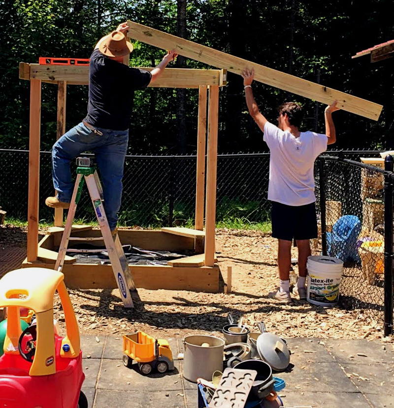 Shawn Chando (left) and John Giuliano build a shelter over a sandbox at Coastal Kids Preschool in Damariscotta on Tuesday, July 16. (Photo courtesy Lisa Conway)