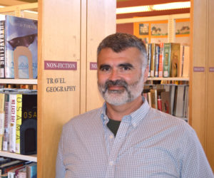 Matthew Graff, the incoming executive director at Skidompha Library in Damariscotta, stands among the bookshelves June 24. Graff officially took the reins Monday, July 1. (Evan Houk photo)