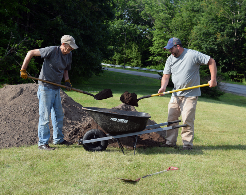 Boothbay Harbor Rotary Club member Bill Prince (left) and Edgecomb Eddy School Principal Ira Michaud shovel soil into a wheelbarrow for another raised bed. (Jessica Clifford photo)