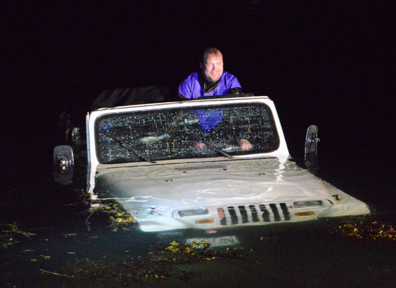 Local diver David Gallagher steers a Jeep Wrangler as a truck pulls it out of the water at Eugley Landing in South Bristol the night of Monday, July 29. Quick Turn Auto Repair and Towing Inc., of Damariscotta, pulled the Jeep out. (Evan Houk photo)