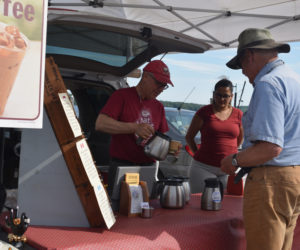 Roastmaster Dan Sortwell, of Wiscasset's Big Barn Coffee Co., pours a cup of coffee for customer Fred Bowers as Melissa Castilla looks on at the Wiscasset Farmers Market. (Jessica Clifford photo)