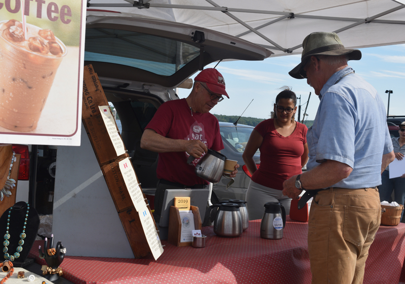 Roastmaster Dan Sortwell, of Wiscasset's Big Barn Coffee Co., pours a cup of coffee for customer Fred Bowers as Melissa Castilla looks on at the Wiscasset Farmers Market. (Jessica Clifford photo)