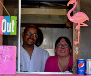 Alex Echevarria and Daisey Cunningham, of Wiscasset, stand behind the counter of their Puerto Rican food stand, Maritza's Place, at Montsweag Flea Market in Woolwich on July 3. (Nettie Hoagland photo)
