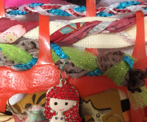 Many strands of braided materials, a mermaid included, are woven through a grid of orange construction fencing to create a large community tapestry during the June 27 Wiscasset Art Walk.