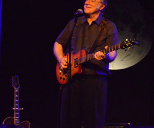 John Sebastian, with an enlarged image of the moon as his backdrop, delights the sold-out crowd out the Opera House at Boothbay Harbor with plenty of stories and song on Thursday, July 25. (Evan Houk photo)