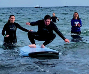 CLC YMCA staff members Molly Cyr (left) and Lori Tozier support a Special Surfer on the water in August 2018. (Photo courtesy Karen-Ann Hagar)