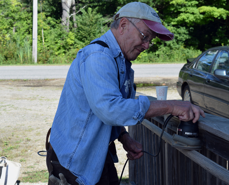 Chip Inc. volunteer Gerry Brookes sands a handrail at Lincoln County Dental Inc. in Wiscasset on Friday, Aug. 23. (Jessica Clifford photo)