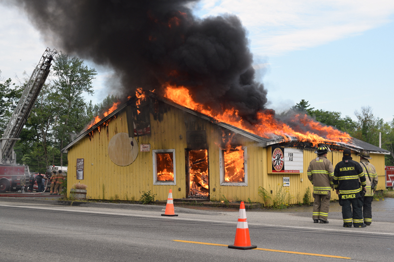 Local firefighters watch the circa-1960s Huber's Market building go up in flames during a training exercise in Wiscasset on Sunday, Aug. 4. The site will become part of the parking lot for a new Dollar General store. (Jessica Clifford photo)