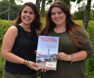 Amanda Reibel (left), the marketing and community relations specialist for Servpro of Bath/Brunswick, and Maia Zewert, the marketing and engagement coordinator for The Lincoln County News, hold a copy of the 2019 edition of the Lincoln County Road Atlas. (Amber Clark photo)