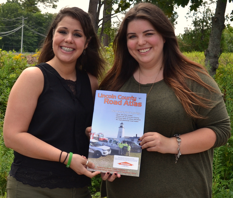 Amanda Reibel (left), the marketing and community relations specialist for Servpro of Bath/Brunswick, and Maia Zewert, the marketing and engagement coordinator for The Lincoln County News, hold a copy of the 2019 edition of the Lincoln County Road Atlas. (Amber Clark photo)