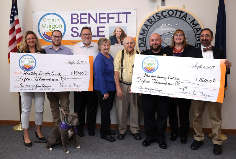 The family behind Oranges from Morgan presents $15,000 checks to Healthy Lincoln County and the Midcoast Recovery Coalition at the Damariscotta town office Friday, Sept. 6. From left: Jess Breithaupt, of Healthy Lincoln County; Derek Mayo, with Marley; Joe Mayo; Florence and Ernest Bourgon; Damariscotta Police Chief Jason Warlick; Tamra Mayo; and Dr. Ira G. Mandel, of the Midcoast Recovery Coalition. (Photo courtesy John Maciel)