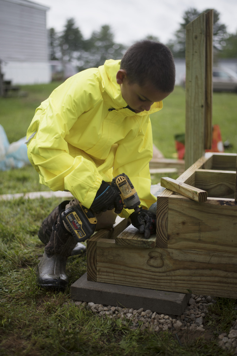 Jack Heller, 10, of Waldoboro, uses a drill as he works on a new set of stairs at East Ridge Mobile Home Park in Waldoboro on Community Cares Day, Saturday, Sept. 7. (Jessica Picard photo)