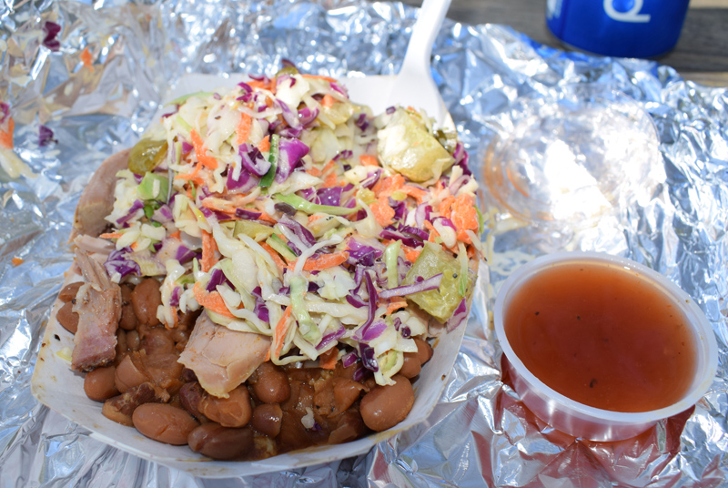 The "Hillbilly Sundae," with a side of tangy sauce, from the Sweet Georgia BBQ food stand at 67 Main St. in Newcastle. The dish consists of a base of cornbread with layers of baked beans, pulled pork, and coleslaw. (Evan Houk photo)