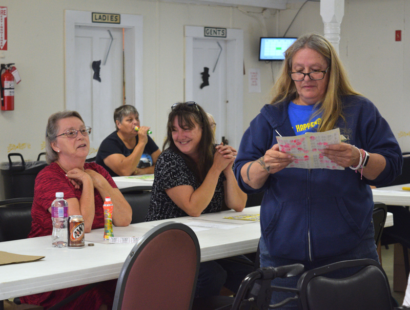 From left: Cindy Bailey and Charlotte Simmons wait with anticipation as Huntoon Hill Grange member Debbie Kovacs reviews Bailey's bingo card during the Smerdon family benefit at the Grange in Wiscasset on Sunday, Sept. 22. (Jessica Clifford photo)