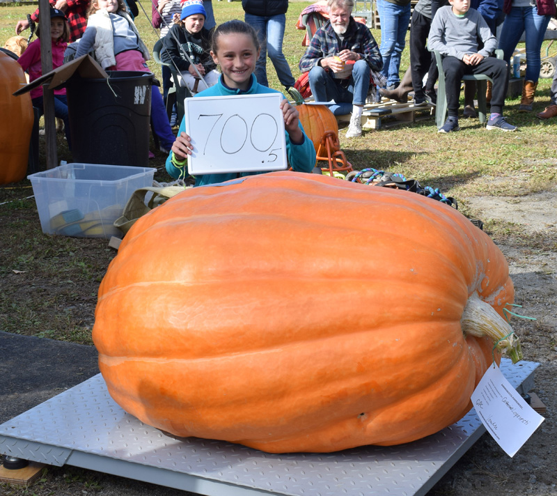 Catherine Lopresti, daughter of master of ceremonies Charlie Lopresti, stands with her 700.5-pound pumpkin. The pumpkin took first place in the youth category and won the Howard Dill Award for prettiest pumpkin over 500 pounds. (Evan Houk photo)