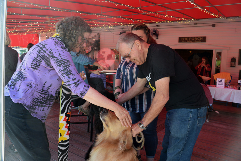 The Rev. Maria Hoecker, of St. Columba's Episcopal Church in Boothbay Harbor, blesses Decker, while Jim Singer holds the dog's leash during the Action for Animals Maine launch party at Brady's restaurant. (Jessica Clifford photo)