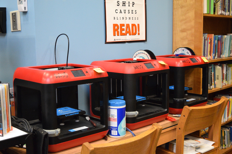 A row of 3D printers in the learning commons at Whitefield Elementary School. Students are using the technology more this year. (Jessica Clifford photo)