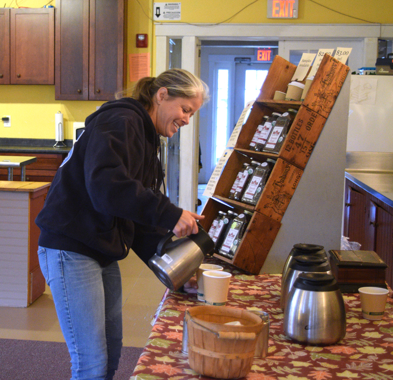 Crystal Lewis pours cream into her coffee at The Morris Farm, the location for the Wiscasset Winter Farmers Market. (Jessica Clifford photo)
