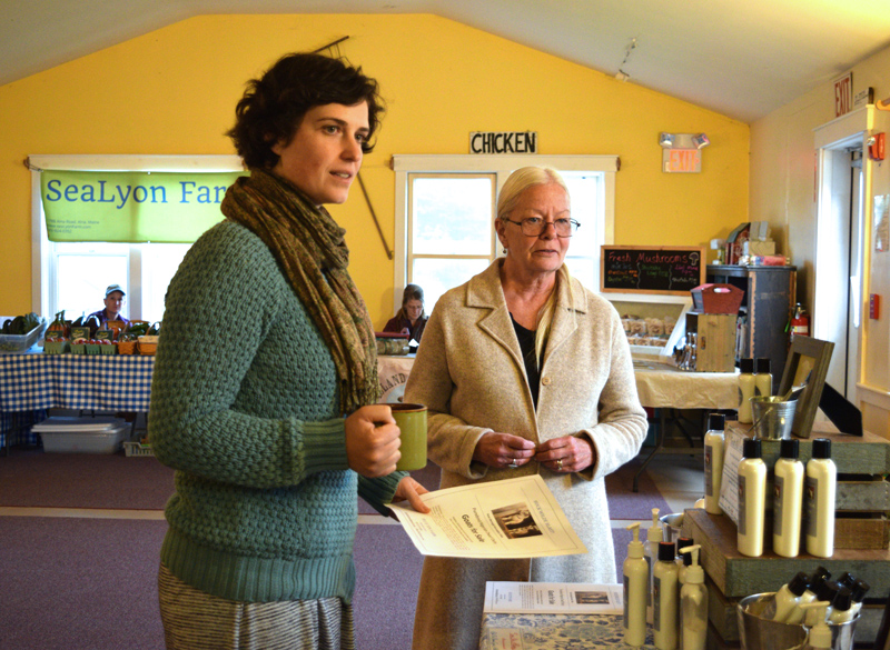 Anna Blank, farm education director for The Morris Farm, stands next to Penny Theall in front of the Blue Tin Farm stand at the Wiscasset Winter Farmers Market on Thursday, Oct. 17. (Jessica Clifford photo)