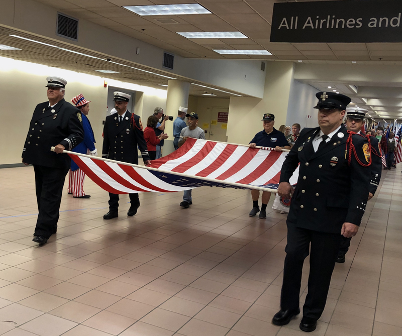 Maine firefighters carry the American flag during the Honor Flight Maine homecoming parade at the Portland International Jetport on Sept. 22. (Photo courtesy Kathleen Onorato)