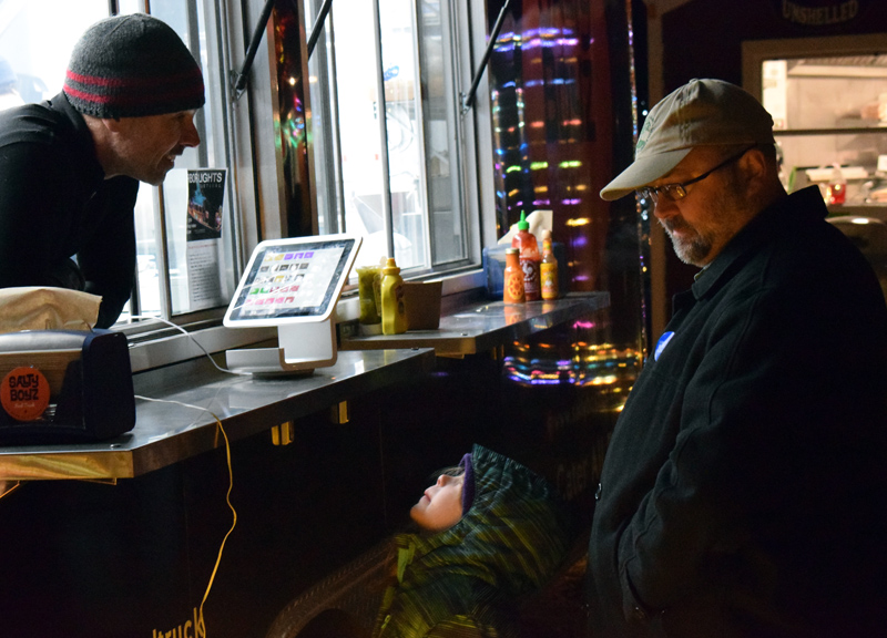 A young patron struggles to see over the counter to place an order with Warren Busteed, owner of the Salty Boyz food truck, at Food Trucks A-Go, the new food truck court on Route 27 in Boothbay, Saturday, Nov. 23. (Evan Houk photo)