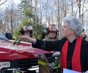 The Rev. Katherine Pinkham, chaplain of the Edgecomb Fire Department, blesses Squad 4 with a pine branch and water as firefighters look on during a ceremony at the station Sunday, Nov. 3. (Jessica Clifford photo)